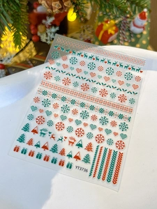 Detailed view of Christmas nail art stickers featuring elk and snowflakes on festive background