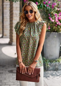 Outdoor street style shot of women's sleeveless green floral blouse with ruffle shoulders