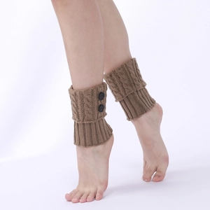 Detail of brown cable knit leg warmers with decorative buttons on model's boots