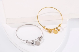Detail of adjustable stainless steel heart and vintage coin pendants on gold and silver bangles