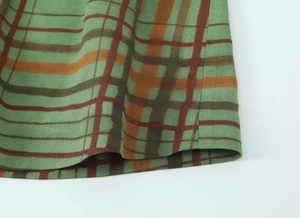 Close-up of green plaid blazer stitching showing twill fabric texture and sewing detail