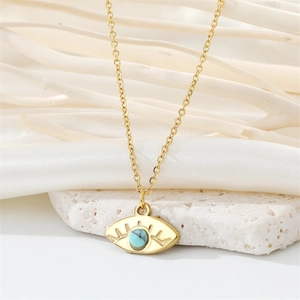 Detail of a golden evil eye pendant with a blue bead on a white textured stone