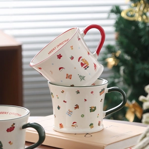 Close-up of stacked ceramic Christmas mugs with Santa patterns and Merry Christmas text