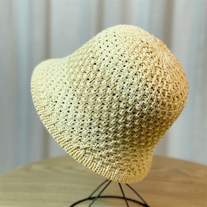 Detail of delicate woven texture on a beige sun hat placed on a black metal stand
