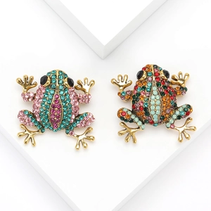 Luxurious gold-tone frog brooches with colorful rhinestones on minimalist white display