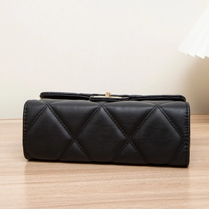Quilted crossbody bag with gold twist-lock closure on a light wood background