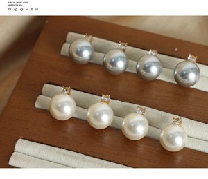 Detail von Titanstahl-Ohrringen mit Perlen und Strass auf einem Schmuckdisplay aus Holz