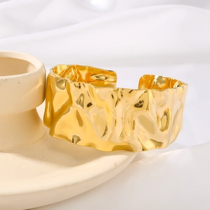 Modern 18K gold-plated wide cuff bracelet with textured hammer finish on ceramic stand