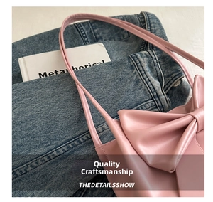 Detail of pink leather tote bag featuring a large decorative bow and fine stitching
