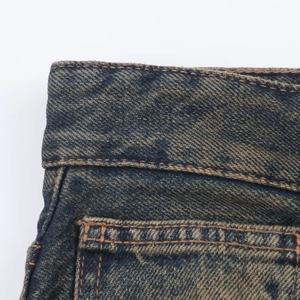 Vista macro de la cintura de mezclilla lavada vintage con costuras reforzadas en jeans