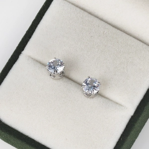 Close-up of classic 4-prong silver cubic zirconia stud earrings in a green velvet box