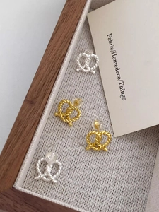 Detailed view of gold and silver twisted rope love knot earrings in a wooden jewelry box