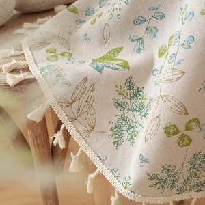 Detailed close-up of a floral cotton linen tablecloth with elegant beige fringes