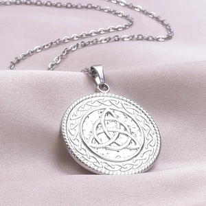 Macro shot of silver Triquetra Celtic knot pendant on silk background showing fine details