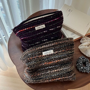 Close-up of vintage wool tweed cosmetic bags with woven texture and a brand logo patch