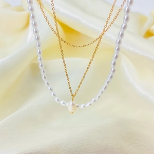 Detail of double-layer necklace with baroque pearl pendant and white bead chain on silk