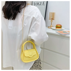Mini macaron yellow jelly bag with gold chain strap shown on model in modern room