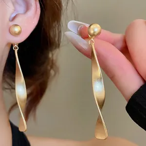 Boucles d'oreilles pendantes ruban torsadé en or mat avec clous perle au style épuré