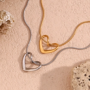 Flat lay of gold and silver heart pendants on delicate snake chains over stone textures