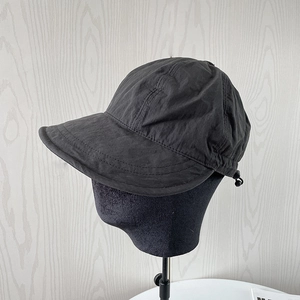 Detail view of adjustable drawstring and plastic toggle on black nylon sun hat side