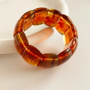 Macro detail of acrylic tortoise shell bracelet featuring amber resin texture and wide bands