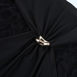 Détail de dentelle florale et boucle métallique dorée à trois anneaux sur robe noire chic