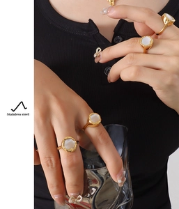 Close-up of gold stainless steel ring with white shell inlay on a female hand