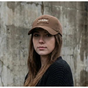 Detail of distressed brown cotton baseball cap featuring vintage embroidery and frayed edges