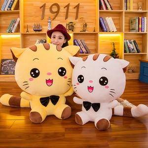 Close-up of yellow and white striped plush cats with black bow ties on wooden shelf