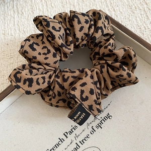 Close-up of leopard print hair scrunchie with embroidered handmade label details