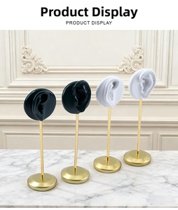 Set of 4 black and white ear-shaped jewelry stands with gold metal poles on marble surface