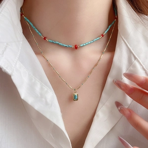 Detail of layered bohemian necklace with turquoise beads and gold rectangular pendant
