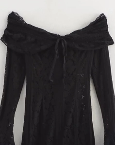 Detail of elegant black lace off-the-shoulder dress featuring a delicate bow tie neckline