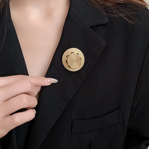 Detailansicht einer goldenen Spiralbrosche an einem Revers eines schwarzen Business-Anzugs