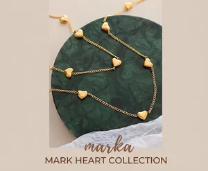 Détail du collier cœur doré sur marbre vert avec des pendentifs polis en 3D
