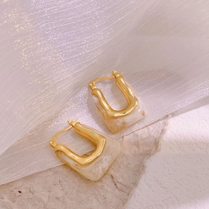 Detailed shot of U-shaped gold-plated earrings with off-white marble resin inlay