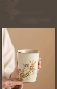 Close-up of a Ru-kiln ceramic teacup with a hand-painted cat and floral pattern design