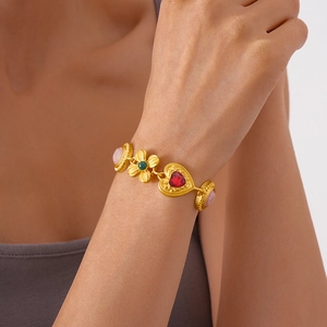 Close-up of heart and flower gold bracelet with colorful gems worn on a wrist