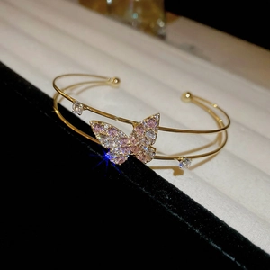 Detailed macro of gold butterfly bangle with pink and white zircon stone setting
