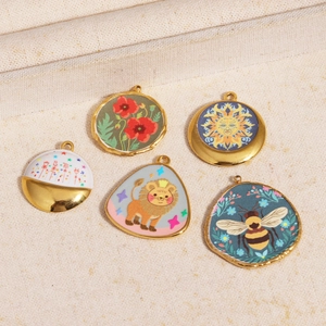 Detailed macro view of gold plated enamel charms featuring bees, poppies, and sun patterns