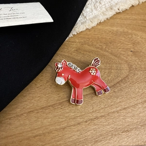 Detailed macro view of a red enamel horse brooch with sparkling rhinestones and gold accents