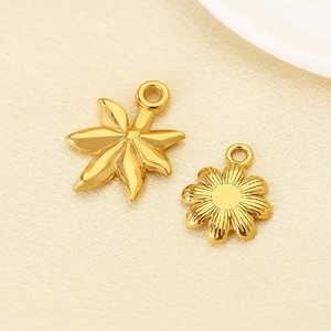 Gold stainless steel flower and daisy pendants on silk fabric background with high gloss