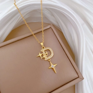 Close-up of gold D-letter star pendant necklace with zircons on silk fabric