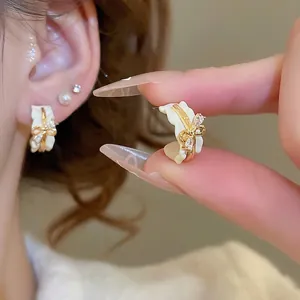 18k gold plated bow C-shape stud earrings with sparkling diamonds and white wavy trim
