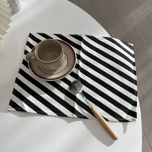 Close-up of black and white diagonal striped woven placemat on a white dining table
