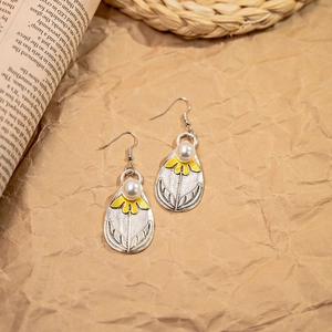 Bohemian vintage teardrop earrings with yellow flowers and pearls on rustic background
