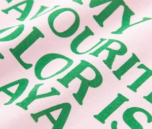 Gros plan de l'impression de lettres vertes sur tricot de coton rose avec texture
