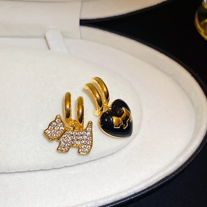Macro shot of asymmetrical Scottie dog earrings with diamond inlay and heart charm