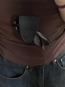 Nahaufnahme des tragbaren schwarzen Brillenclips aus Leder an einem braunen T-Shirt