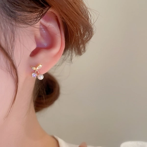 Close-up of cherry design gold earrings with elegant pearls and zircon on model